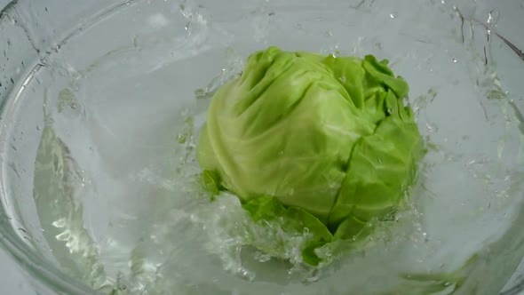 Falling cabbage Brassica oleracea into a glass bowl of water. Slow motion. alt