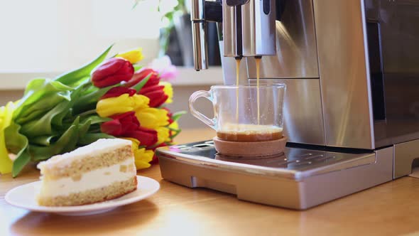 Cup of Coffee with Milk Piece of Cake and Tulips Flowers on Wooden Kitchen Table