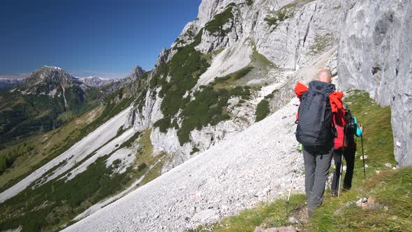 Sporty Couple Hiking Close to Rock Face in Alps