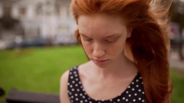 Wind Blowing Hair of Ginger Teen Caucasian Girl While She Looking Down Then at Camera alt