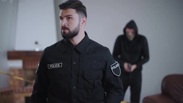 Portrait of Caucasian Police Officer Standing and Looking Around As Criminal Reloading Guns alt