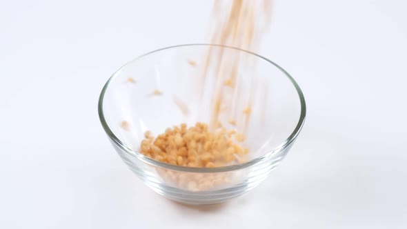 Dry yellow split peas falling into a glass bowl on white background,