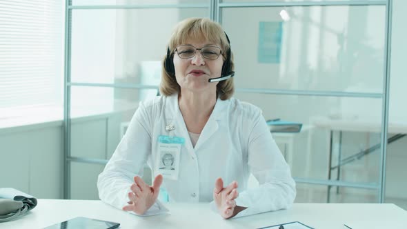 Senior Female Doctor in Headset Giving Online Consultation alt