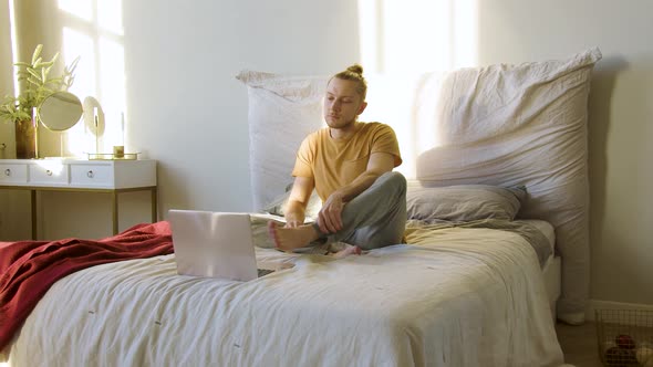 Young Man Chooses an Online Meditation Tuturial and Begins to Meditate alt