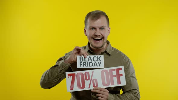 Shocked Amazed Store Client. Man Showing Black Friday and Up To 70 Percent Off Inscriptions Signs alt