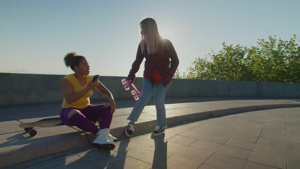 Lovely Multiracial Females with Skateboards Meeting for Ride in Morning alt