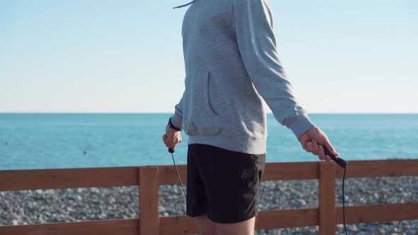 Sportsman Is Jumping Rope in Sunny Day Near Sea alt