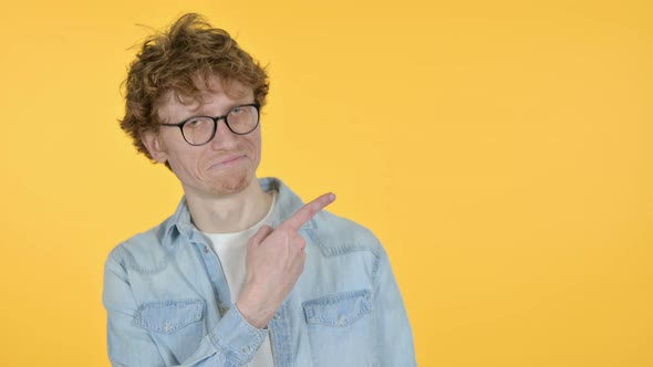Copy Space, Redhead Young Man Pointing with Finger, Yellow Background alt