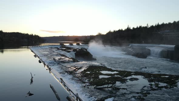 Flying Over a Dam with Waterfalls During Sunset alt