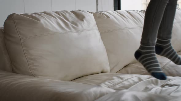 Legs of Active Child Jumping on Couch at Home Closeup Shot alt