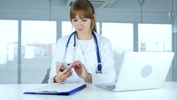 Young Female Doctor Browsing Online on Phone in Hospital alt