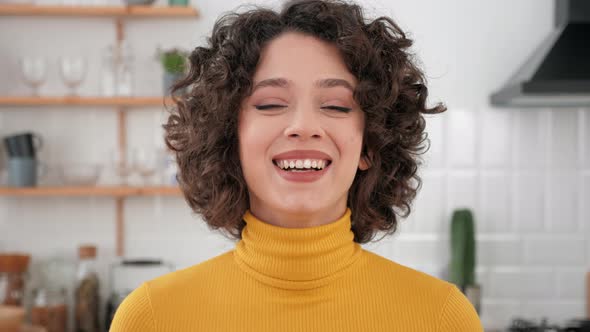 Close Up Face Laughing Hispanic Curly Woman Looking Camera at Home Kitchen alt