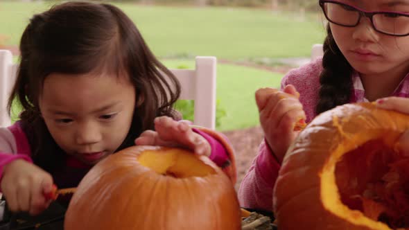 Young girls carving pumpkin for Halloween