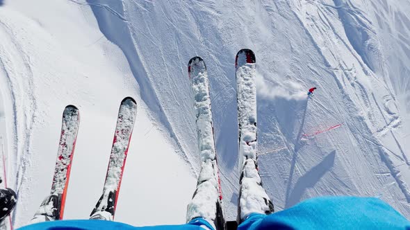 Legs and Two People with Pairs of Skis Dangling Over Tracks alt