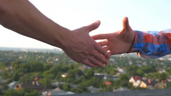 Two Friends Shaking Hands on Blurred Cityscape Background alt