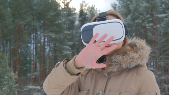 Woman Uses a Virtual Reality Glasses in Winter Forest