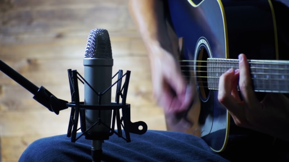 Musician Recording Acoustic Guitar in Microphone on the Home Studio