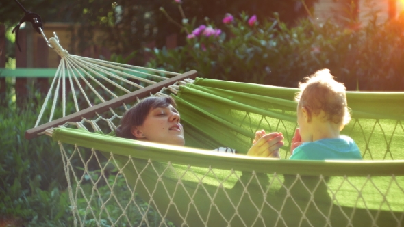 Happy Mother and Her Two Years Old Baby Boy Lying in Hammock