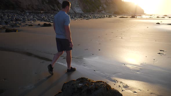 A strong young man walking on the beach after a morning fitness workout at sunrise in Santa Barbara, alt