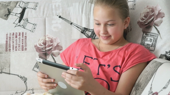 Child Reading a Digital Tablet Lying on the Bed