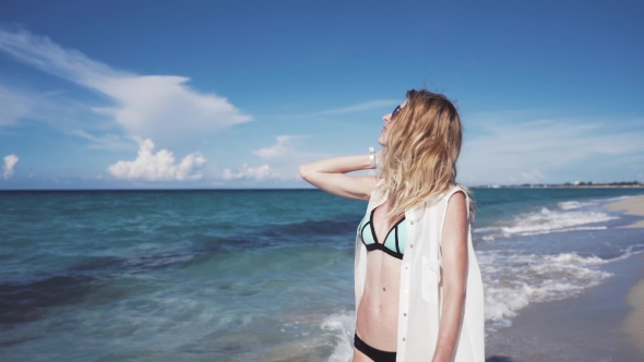 The Beautiful Blonde in a Bikini Walking on the Beach
