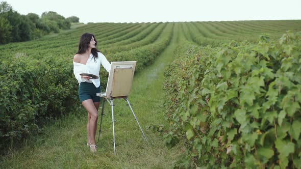 Appealing Brunette Painting a Landscape in Windy Summer Bush Field alt