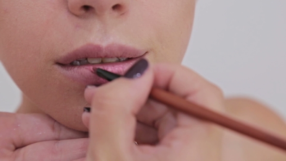 Shot. Professional Makeup Artist Applying Lipstick on Lips of Model