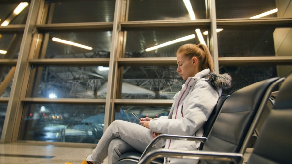 Airline Passenger in an Airport Lounge Waiting for Flight Aircraft