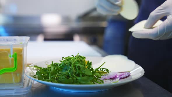 Arugula, cheese and onion on plate. Ingredients for tasty salad. Closeup. alt