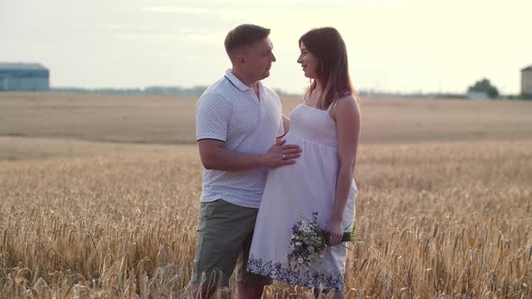 Portrait of Young Pregnant Couple in Field