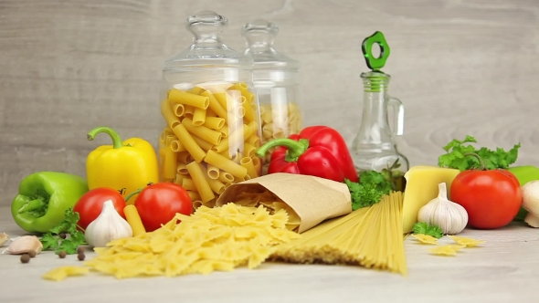 Raw Pasta, Cheese, Olive Oil and Fresh Vegetables on Gray Background alt