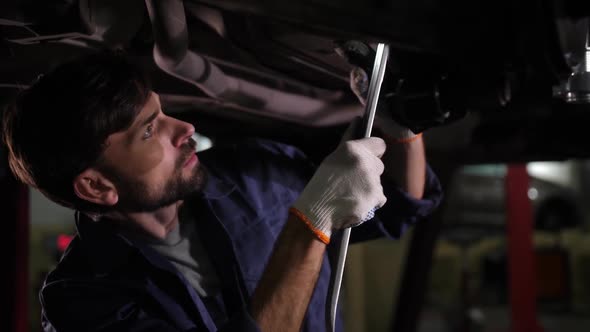 Focused Car Repair Specialist During Chassis Check alt