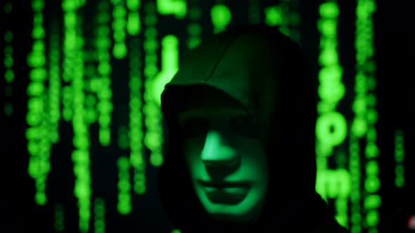 Close Up of a Anonymous Computer Hacker in Black Hood and Mask Over Abstract Binary Matrix alt