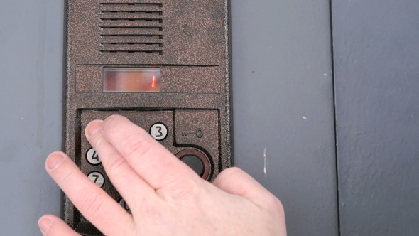Person Dialing Number of Apartment on a Doorphone