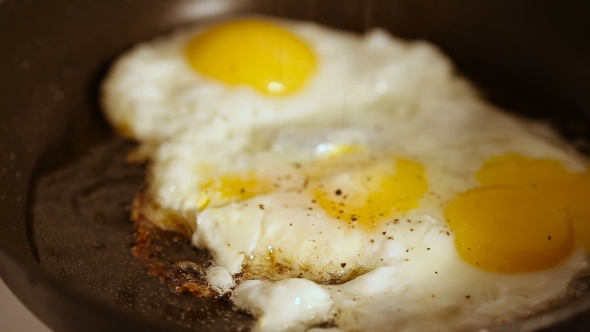Cooking Fried Eggs with Spice in Frying Pan for Breakfast