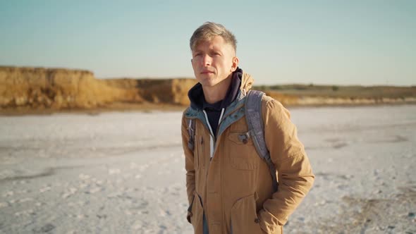 Portrait Confident Man Walking at White Salty Flats and Steep Clay Shore Slow Motion alt