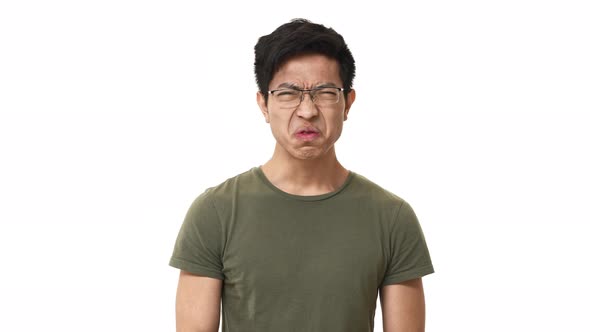 Portrait of Displeased Asian Man 20s Wearing Glasses Frowning While Expressing Disgust and Aversion alt