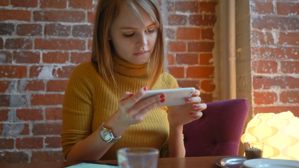 Attractive Woman in a Street Cafe Reading a Text Message From Her Phone