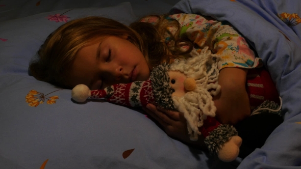Cute Girl Sleeping in Bed Hugging Santa Claus Toy