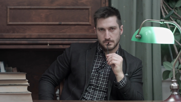 Handsome Young Man Holding Glasses and Looking Into the Camera alt