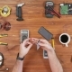 Man Repairing a Mobile Phone. Checks Parts Inside the Device. Wooden Table Top View. - VideoHive Item for Sale