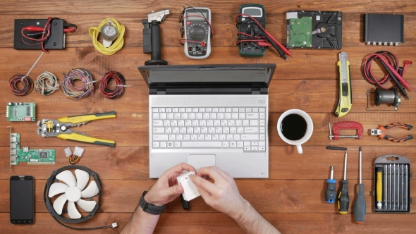 Male Engineer Programmer Copies Files From a Flash Card Action Camera on a Laptop. Wooden Table Top alt
