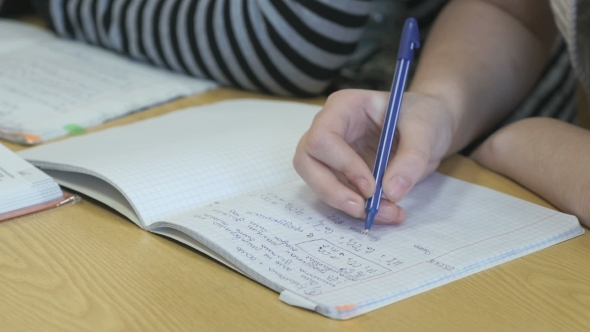 Learner Writes Text in a Exercise Book Using a Pen