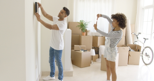 Young Couple Hanging Pictures in Their New Home alt