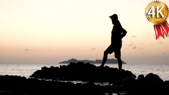 Man Silhouette Standing on a Rock in the Sea