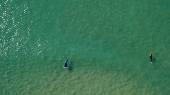 Aerial View of Surfers Riding Green Ocean Waves