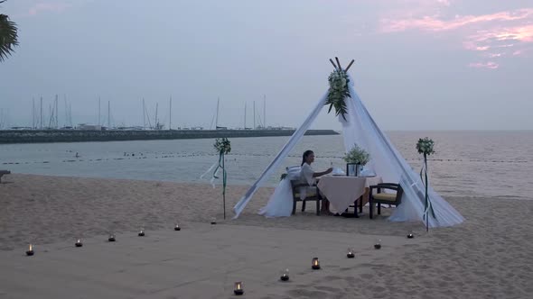 Woman Having Romantic Dinner with Candle Lights on the Beach in Thailand European Men and Asian alt
