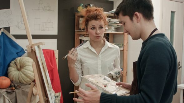 Female Art Teacher Analyzing Painting with Her Male Student alt