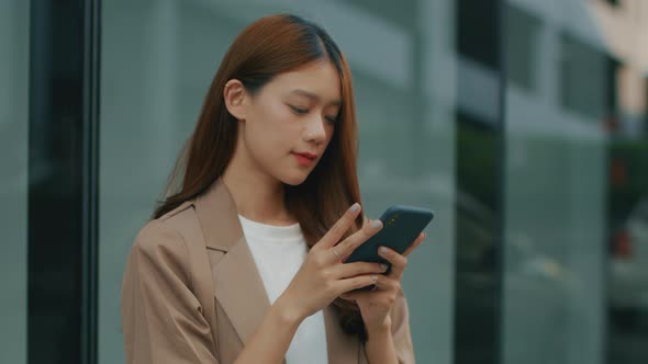 Asian Businesswoman using a mobile phone, working with a smartphone and looking at camera