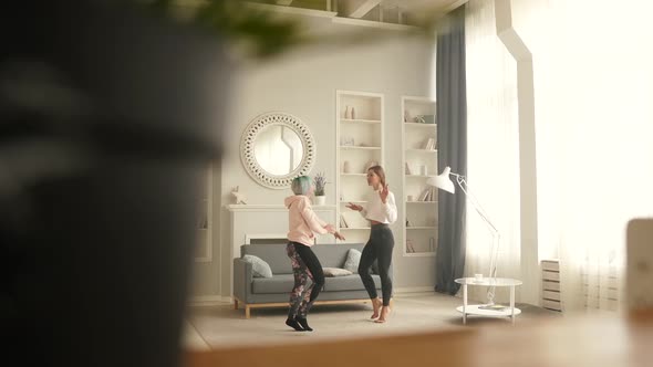Happy Carefree Girls Dance at Home While Listening To Music on the Phone.  alt